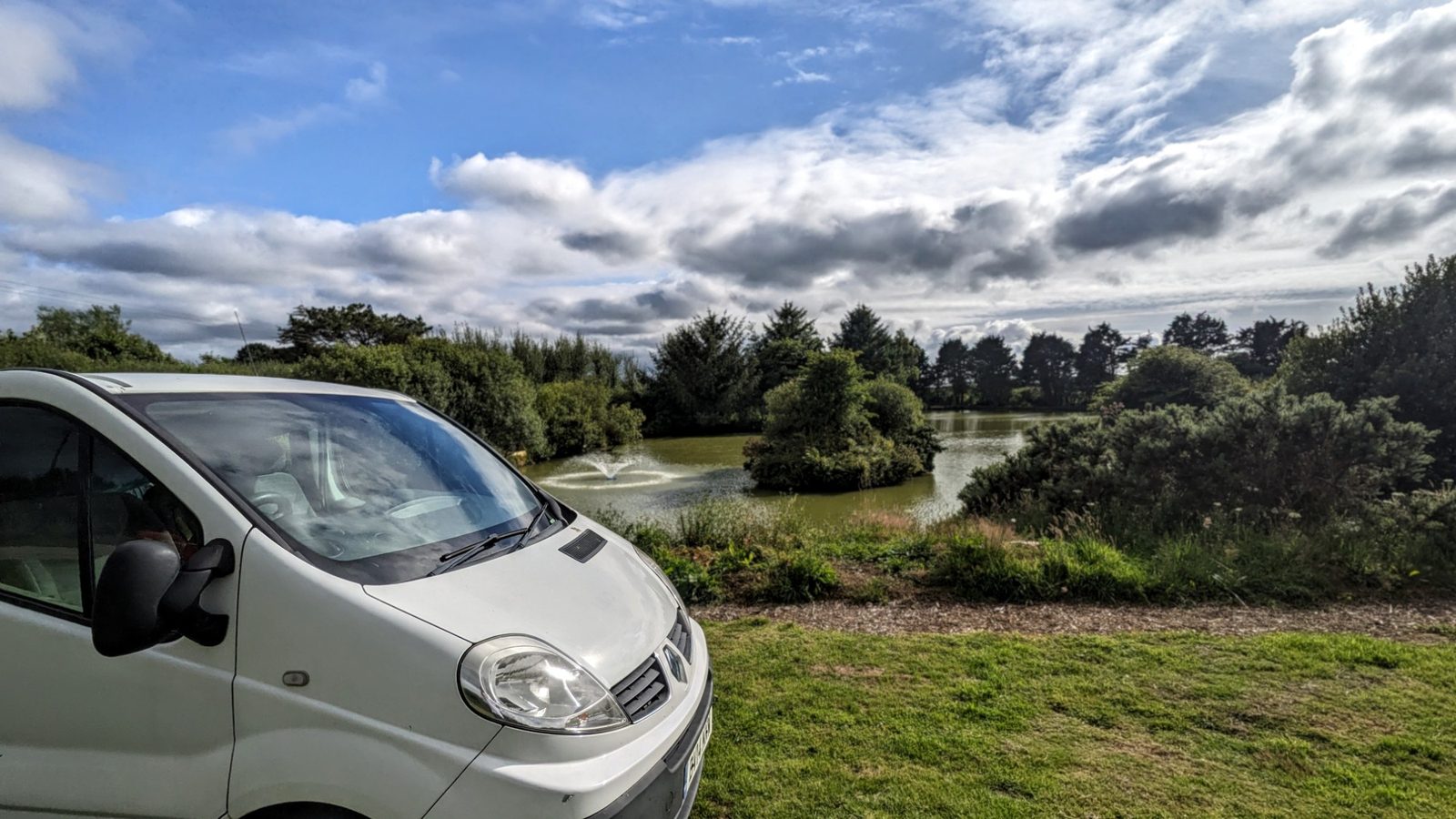 Joe's 2014 Renault Trafic campervan conversion parked by a pond with a fountain