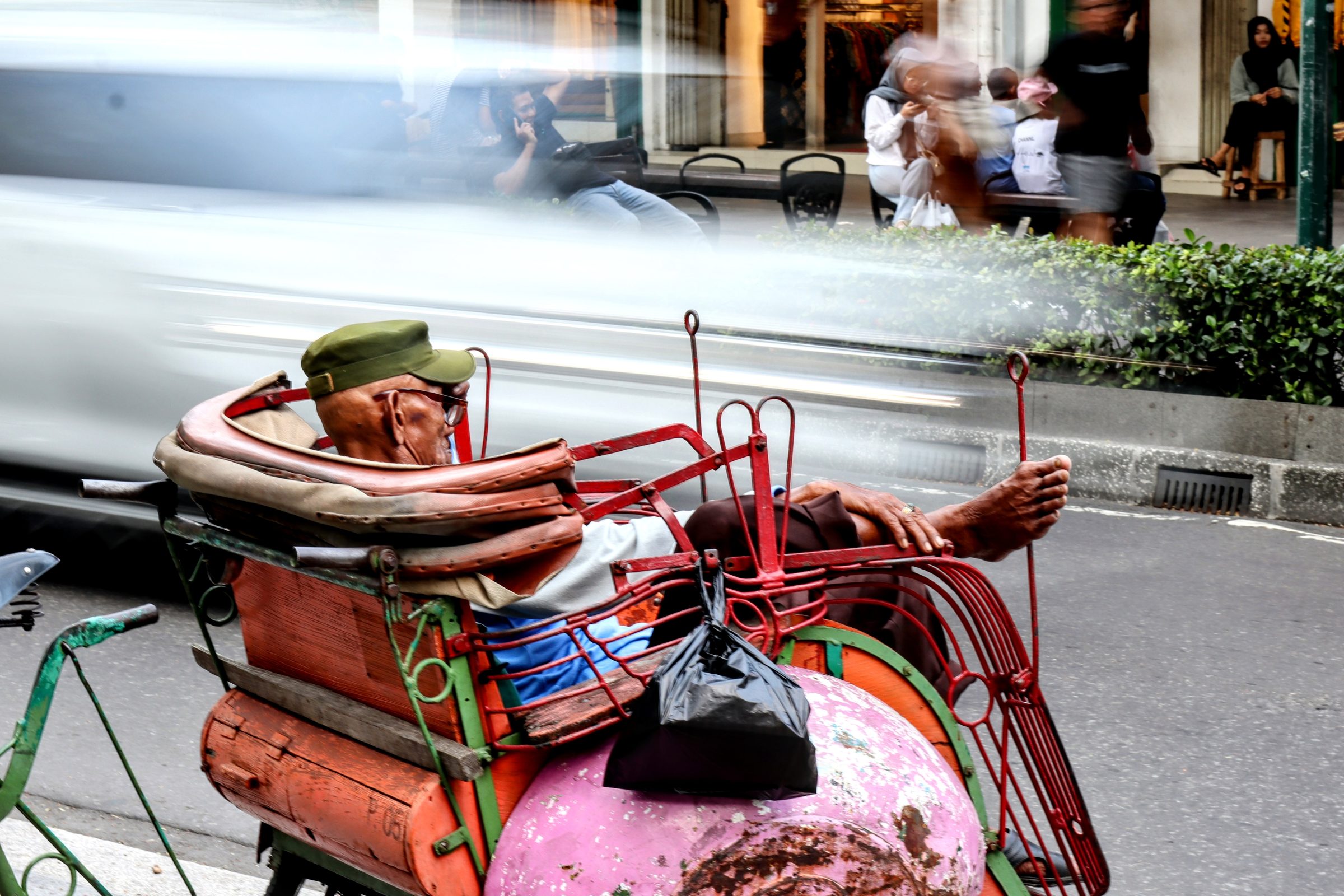 A cycle-rickshaw driver on a street, long exposure