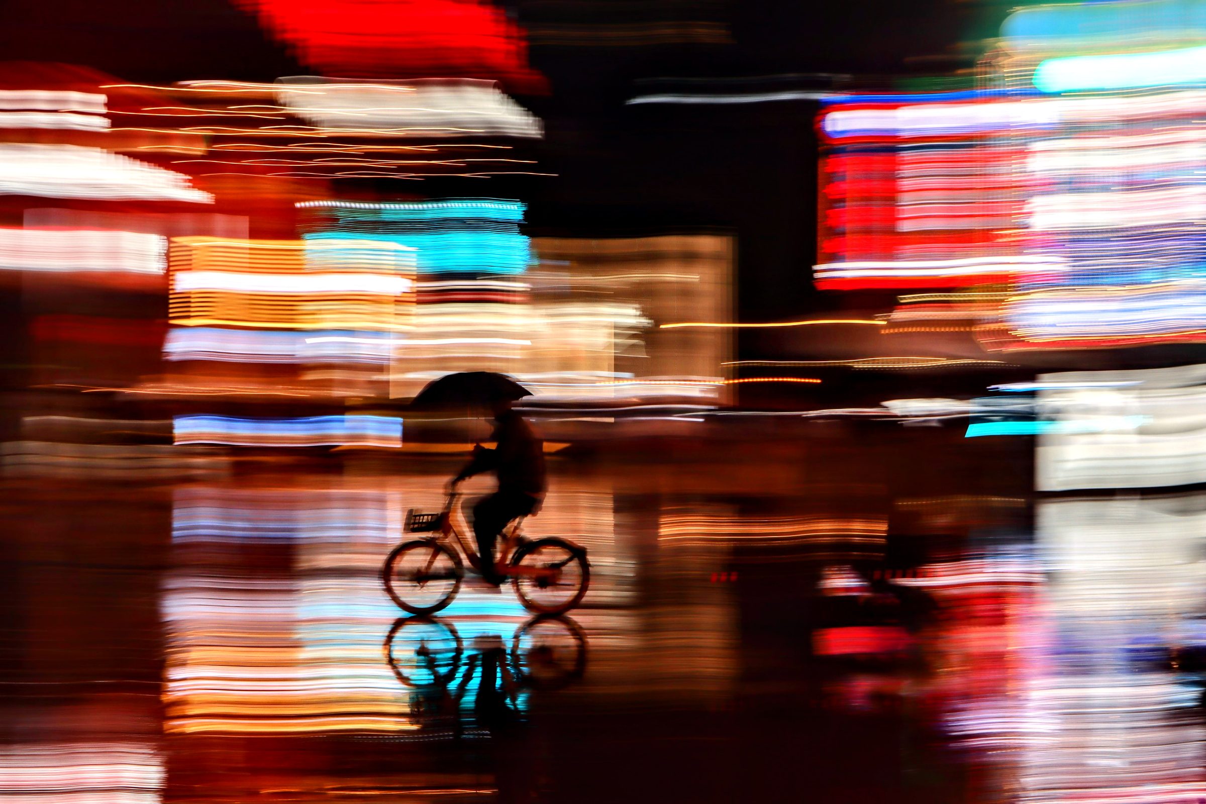 A cyclist with an umbrella at night, long exposure