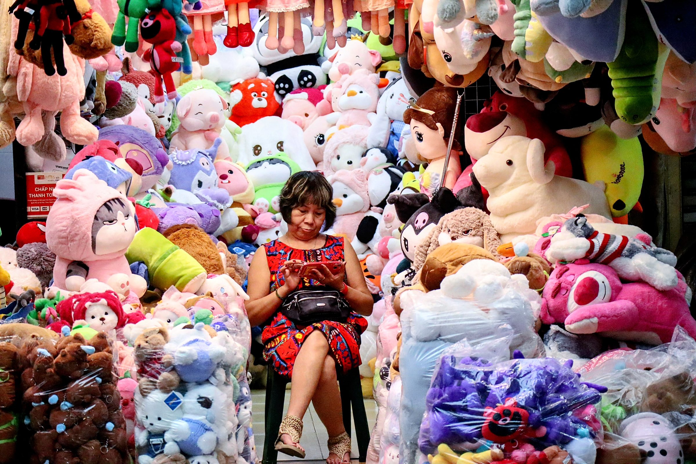A market stall seller surrounded by plush toys
